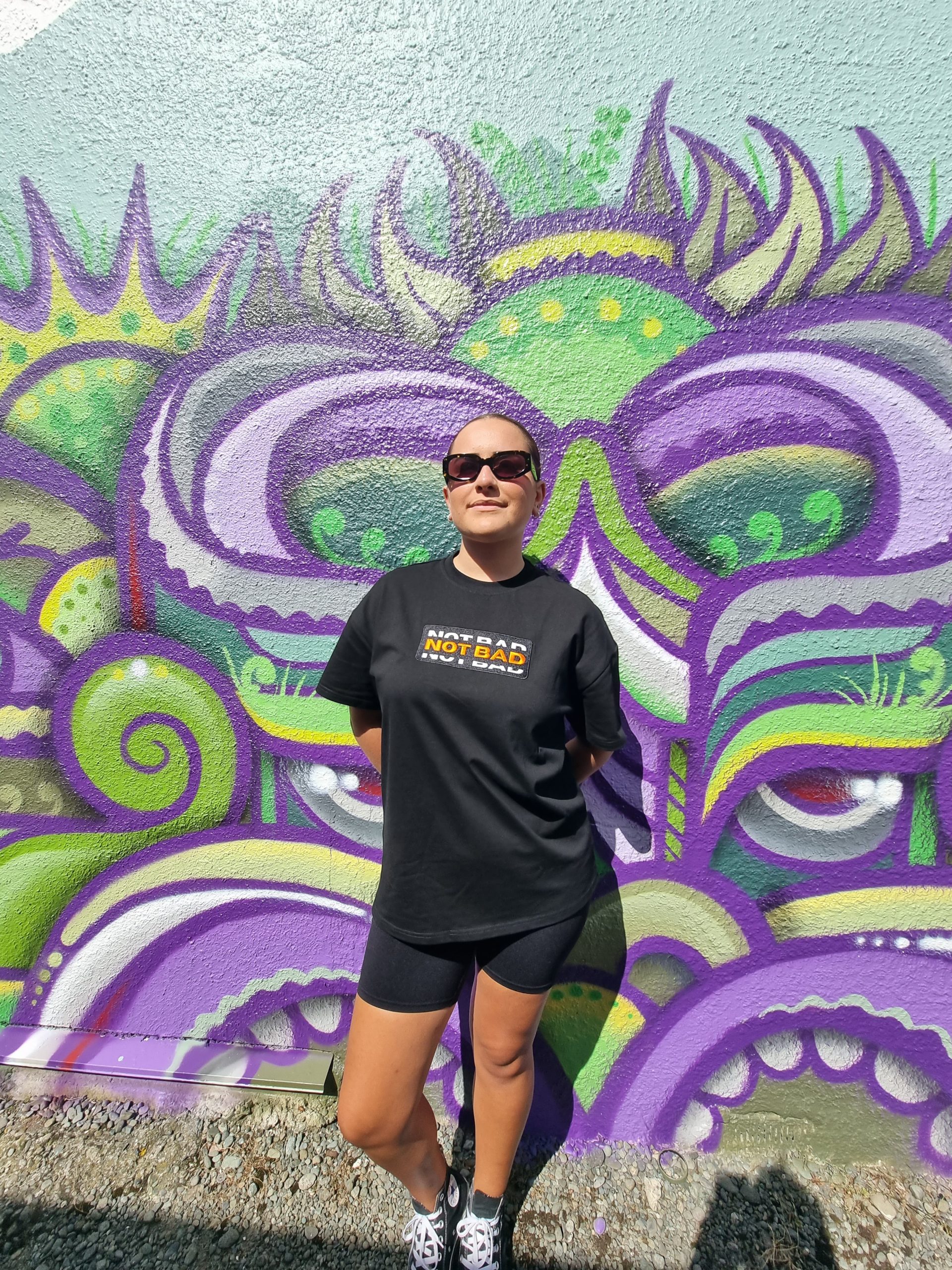 female model using not bad clothing Oversized TEE orange, sunglasses, purple and green graffiti